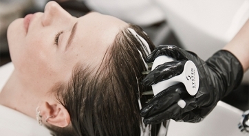 Stylist washes a woman's head at the sink using a System Professional brush